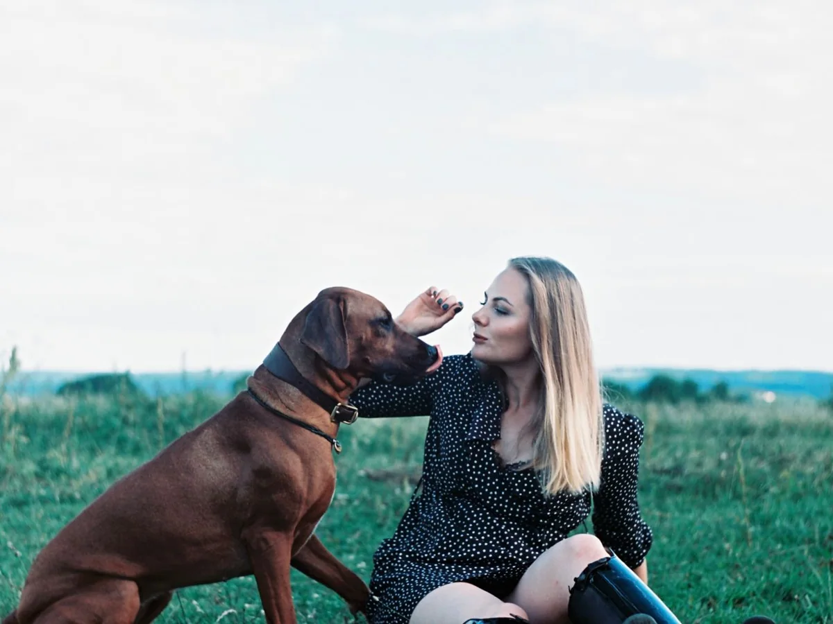 Opiekunka odpoczywa z psem na trawie